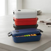 A stack of four lunch boxes in red, white, navy, and blue, featuring a lid and a small logo on each.