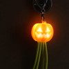 A bright orange pumpkin-shaped light with green charging cables, attached to a keyring, featuring a smiling face.