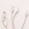 A wheat straw charging cable in a man shape, featuring white and beige tones and multiple connector types.