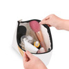 A canvas cosmetic bag in white, filled with various beauty products, including bottles and a makeup brush.
