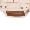 A beige canvas tote bag with brown leather straps and metal studs, featuring a simple design and sturdy construction.