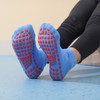 A pair of blue low cut kids' socks with red gripper dots on the soles, laid out against a light background.