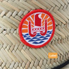 A straw hat with a woven design and a circular label featuring a colourful logo.