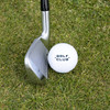 A golf club rests near a white golf ball on green grass, featuring a logo on the ball.