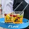 A blue bar serving tray with two glasses containing colourful cocktails garnished with citrus and herbs.