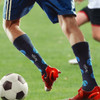 A pair of mid-calf socks in navy with a custom pattern, featuring a logo, worn during a soccer game.