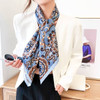A silk chiffon scarf in a blue and brown floral pattern, elegantly knotted around a model's neck.