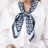 A silk chiffon scarf featuring a floral pattern in blue and white, neatly tied around a person's neck.