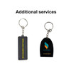 A custom-shaped PVC keyring in black with a metal ring and chain, featuring a logo. Two designs shown.