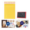 A small padded bubble envelope in yellow, featuring a logo, alongside a rubber stamp and promotional products.