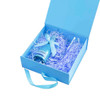 A light blue custom gift box containing a drink bottle and a glass, surrounded by blue shredded paper.