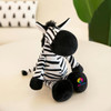 A striped black and white plush zebra toy sits on a light surface, featuring a round body and playful expression.