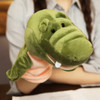 A green crocodile hand puppet with a friendly face and soft texture, held by a person.