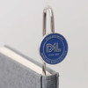 A metal bookmark in silver with a blue circular design, featuring a logo.