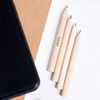 A set of four short, natural wood pencils without erasers, featured alongside a black phone on a light background.