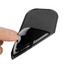 A black dashboard mat being lifted, showcasing its textured surface and flexible design.