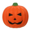 A smiling orange pumpkin stress reliever with black facial features and a green stem.