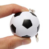 A hand holds a small black and white football-shaped stress reliever attached to a keyring.