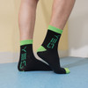Custom pattern woven bamboo socks in black with bright green accents and branding. Suitable for kids' footwear.