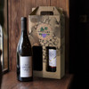 A wine carry pack in brown cardboard with a logo, holding a bottle of Merlot and a larger wine bottle.
