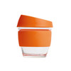 A reusable glass coffee cup with a transparent body and an orange silicone lid and sleeve.