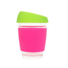 A reusable glass coffee cup in pink with a green lid and a silicone grip. It features a logo on the side.
