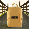 A kraft paper laptop backpack in a tan colour, featuring a logo on the front, set against an outdoor background.