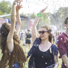 A group of people celebrating outdoors, wearing a green disposable reflective PVC wristband amidst confetti and sunshine.
