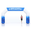 A large inflatable arch in blue and white, featuring a logo, with a runner passing through it.