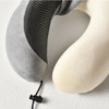A grey and cream U-shaped memory foam travel pillow with a textured surface and a toggle cord.