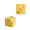 Square cheese-shaped candles in a pale yellow colour, featuring small holes and a wick on top.