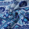 A close-up of a blue and light blue knitted fabric featuring decorative patterns and cartoonish bear motifs.
