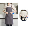 A grey poly-cotton canvas full bib apron with a neck strap, featuring a front pocket and a logo.