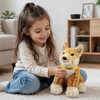 A plush dingo toy in golden-brown sits beside a smiling girl on a soft rug in a bright room.