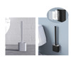 A silicone toilet brush in white and black, showcased on a bathroom floor and attached to a wall.