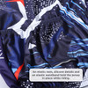 A close-up of a cycling jersey featuring a vibrant blue and abstract pattern, with an elastic hem and waistband.