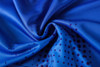 A close-up of a blue polyester spandex fabric featuring a pattern of small purple dots.