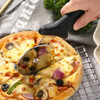 A black pizza cutter with a rounded blade is cutting a cheese and vegetable pizza on a wire rack.