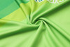 A close-up of a vibrant green fabric, showcasing a smooth texture with a subtle swirl pattern. The material has a logo.