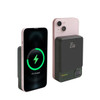 A magnetic wireless power bank in black, next to a smartphone displaying a charging indicator. Features a digital power level display.