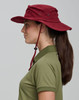 A burgundy surf hat with a wide brim and adjustable chin strap, worn by a person in profile.