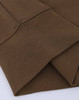 A close-up of a folded brown crew neck sweatshirt featuring ribbed cuffs and a subtle texture. Designed with a logo.