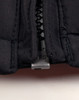 A close-up of a black heavy quilted jacket, highlighting the zip and stitching details. The jacket features a logo.