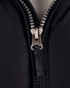 A heavy quilted black jacket with a silver zip featuring the brand logo, showcasing a close-up of the zipper area.
