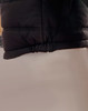 A black heavy quilted puffer jacket featuring a cinched hem and a smooth fabric texture. It has a logo visible.
