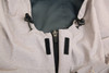 A close-up of a light grey waterproof performance jacket, featuring adjustable toggles and zip fastening.