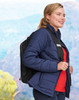 A navy insulated puffer jacket with a fitted cut, worn by a woman carrying a backpack.