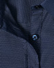 A navy blue ladies' button-up shirt with a pin dot pattern and a blue button. Features a classic collar design.