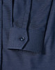 A navy blue pin dot stretch long sleeve shirt with a buttoned cuff and a branded logo.