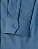 A close-up of a blue pin dot stretch long-sleeve shirt featuring a buttoned cuff and a patterned fabric.